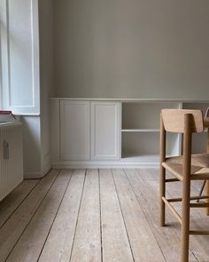 an empty room with two wooden chairs and a radiator in the corner,