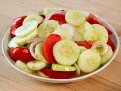 a white bowl filled with sliced vegetables on top of a wooden table