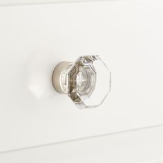 a close up of a knob on a white cabinet with an empty glass door handle