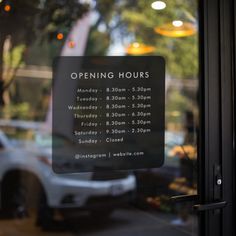 an open hours sign in the window of a restaurant with cars parked behind it and trees outside