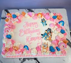 a birthday cake with pink and white frosting on a marble slabd countertop