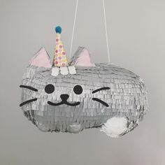 a cat pinata hanging from a string with a party hat on it's head