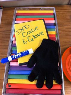 a pair of black gloves sitting on top of a pile of colored pencils