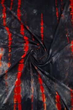 an orange and black tie - dyed fabric with red streaks in the center on a dark background