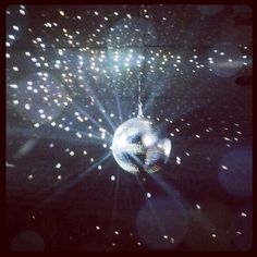 a disco ball hanging from the ceiling in front of some bright lights and sparkles