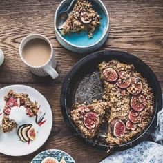 a wooden table topped with plates of food and cups of coffee