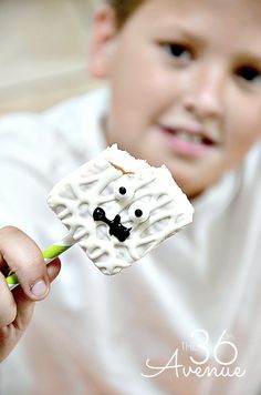 a young boy is holding up a marshmallow shaped like a sheep with eyes and nose