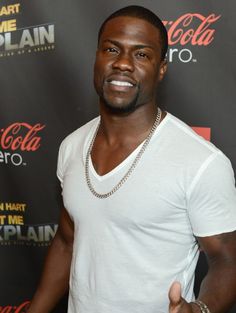 a man in white shirt giving the thumbs up at an event with coca cola on it