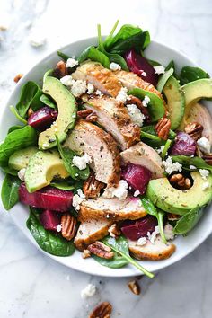 a salad with chicken, avocado, beets and feta cheese on top