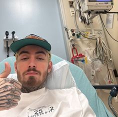 a man in a hospital bed giving the thumbs up with tattoos on his arms and shoulder