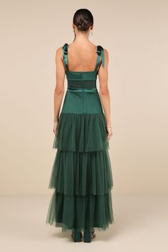 the back of a woman wearing a green dress with ruffles and straps on it