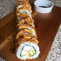 a sushi roll on a cutting board next to a cup of coffee