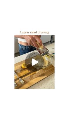 a person is grating lemons in a bowl on a cutting board with the words caesar salad dressing