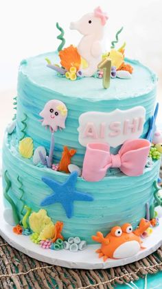 a blue cake decorated with sea animals and under the sea words on it's side