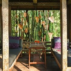 an outdoor seating area with two couches and a table in front of bamboo trees