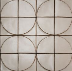 four circles are arranged in the center of a square tile wall pattern, which is white and brown