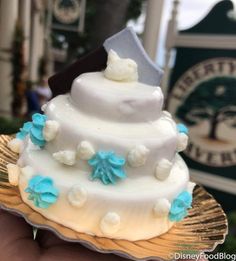 a white and blue wedding cake sitting on top of a gold plate