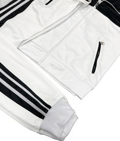 a white and black track suit with zippers on the bottom, two side pockets