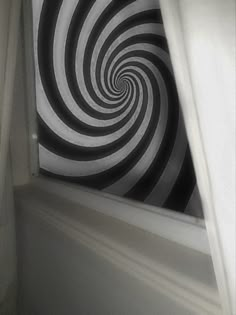 a black and white spiral design is seen through the curtain