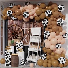 a room filled with lots of balloons and cow print decorations on the wall above it