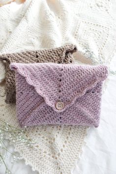 two crocheted purses sitting on top of a white blanket