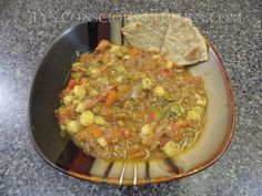 a bowl filled with soup on top of a table next to a slice of bread