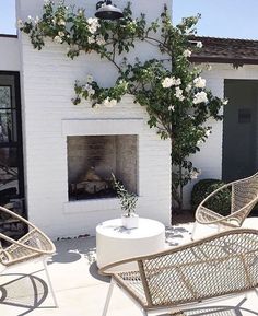 an outdoor fireplace with white paint and wicker furniture