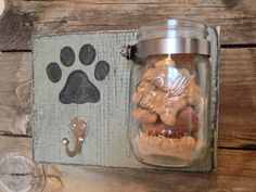 a glass jar filled with dog paw prints on a wooden shelf next to a metal hook