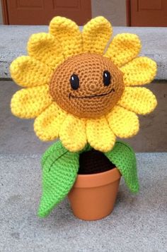 a crocheted sunflower sitting on top of a flower pot in front of a door