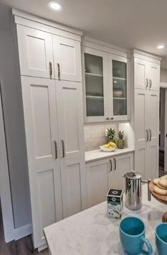 a kitchen with white cabinets and blue cups on the counter top in front of it