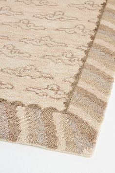 a beige rug with an intricate design on the top and bottom corner is laying on a white surface