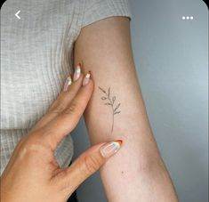 a woman's arm with a small flower tattoo on the left side of her arm