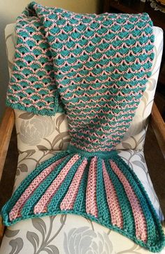 a knitted blanket sitting on top of a chair next to a pillow and throw