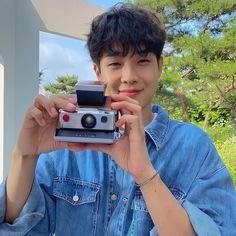 a young man holding up an old camera