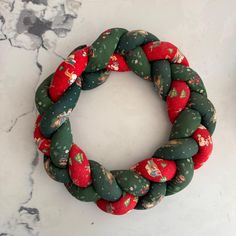 a green and red christmas wreath on a marble surface