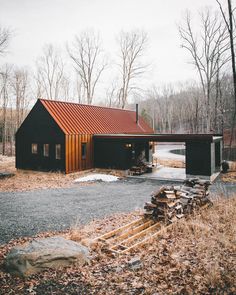 a house with a red roof and lots of wood on the ground in front of it