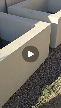 two cement planters sitting next to each other on the side of a building with grass