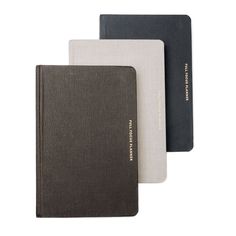 three different colored notebooks sitting next to each other