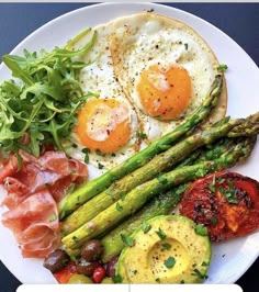 a white plate topped with asparagus, eggs and other food on top of it