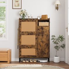 a wooden cabinet sitting in the corner of a room next to a potted plant