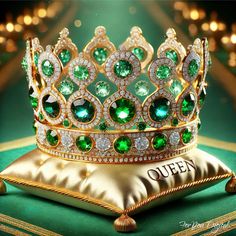 a green crown sitting on top of a pillow next to a gold pillow with the word queen written on it