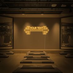 an empty gym with rows of treads in front of a neon sign that reads your text