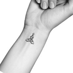 a black and white photo of a hand holding a small tattoo on it's wrist