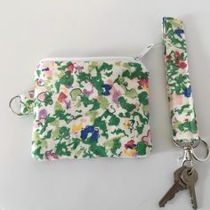 a keychain and pouch sitting next to each other on a white surface with flowers all over it