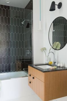 a bathroom with a sink, mirror and bathtub next to a wall mounted shower head