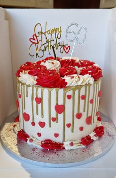 a birthday cake with white frosting and red hearts