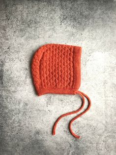 an orange knitted hat laying on top of cement