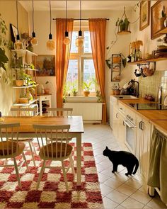 a black cat standing in the middle of a kitchen next to a table and chairs