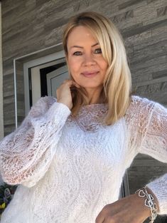 a woman wearing a white sweater posing for the camera with her hand on her hip