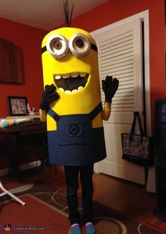 a man dressed as a minion standing in a living room